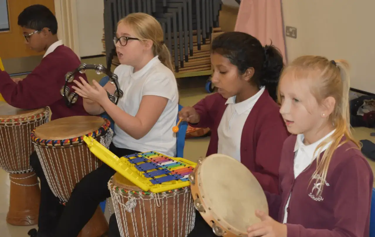 Bambini che suonano tamburi e tamburelli, uno strumento che si suona con le mani, in una lezione di musica.