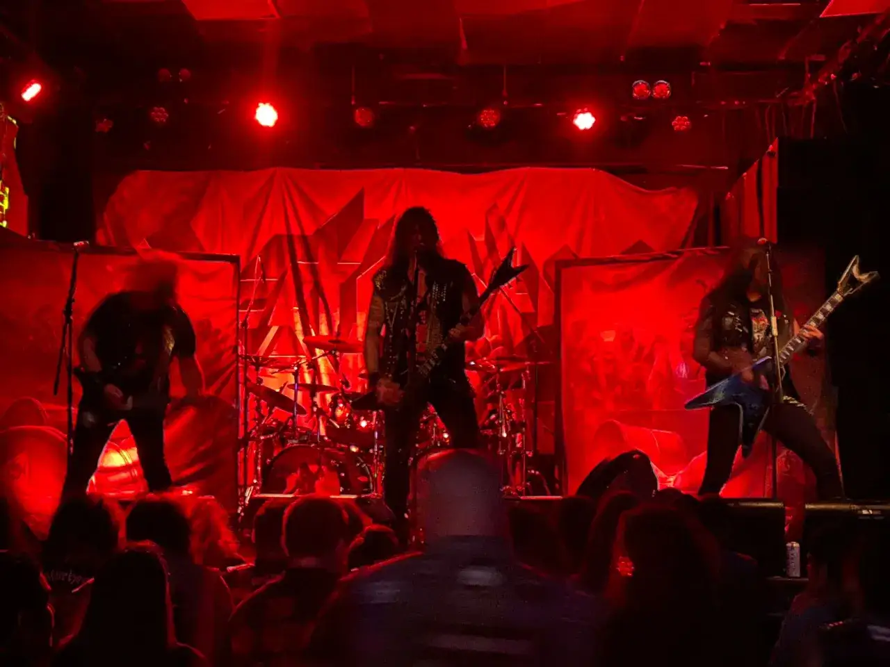 Band metal sul palco, illuminato da luci rosse. Il cantante urla nel microfono, i chitarristi suonano con passione. Sembra una scena da un film horror, ma è solo un concerto, un'esplosione di energia che fa dimenticare il municipal waste quotidiano.