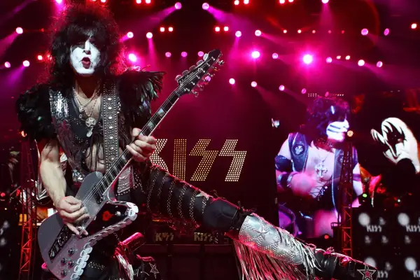 Paul Stanley dei KISS con la sua chitarra, luci rosa e il logo della band. Un momento iconico per chi ama il rock.