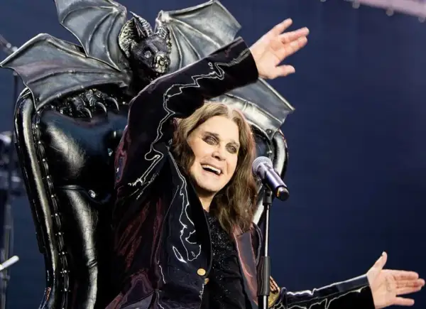 Ozzy Osbourne, icona degli anni '80, canta sul palco con un microfono, dietro di lui un trono demoniaco con ali di pipistrello.
