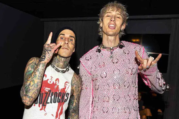 Travis Barker e Machine Gun Kelly, co-compositori, posano con le mani alzate in segno di pace e corna.
