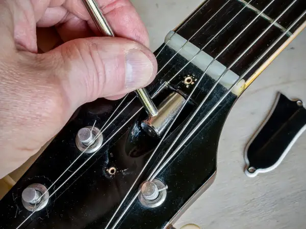 Regolazione del truss rod a doppia azione di una chitarra. La mano usa una chiave per agire sul meccanismo.