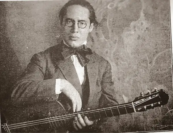 Ritratto di Andrés Segovia, chitarrista, con occhiali rotondi e papillon, mentre suona la sua chitarra.