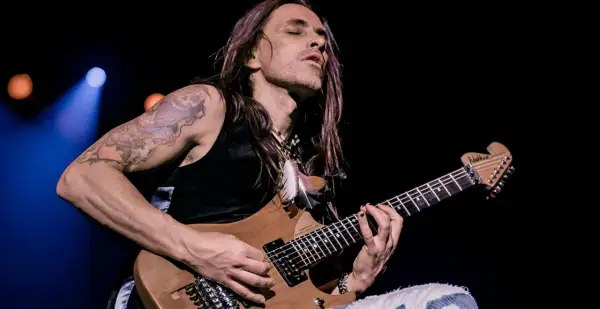 Nuno Bettencourt oggi, con occhi chiusi e capelli lunghi, suona la sua chitarra Washburn con passione.